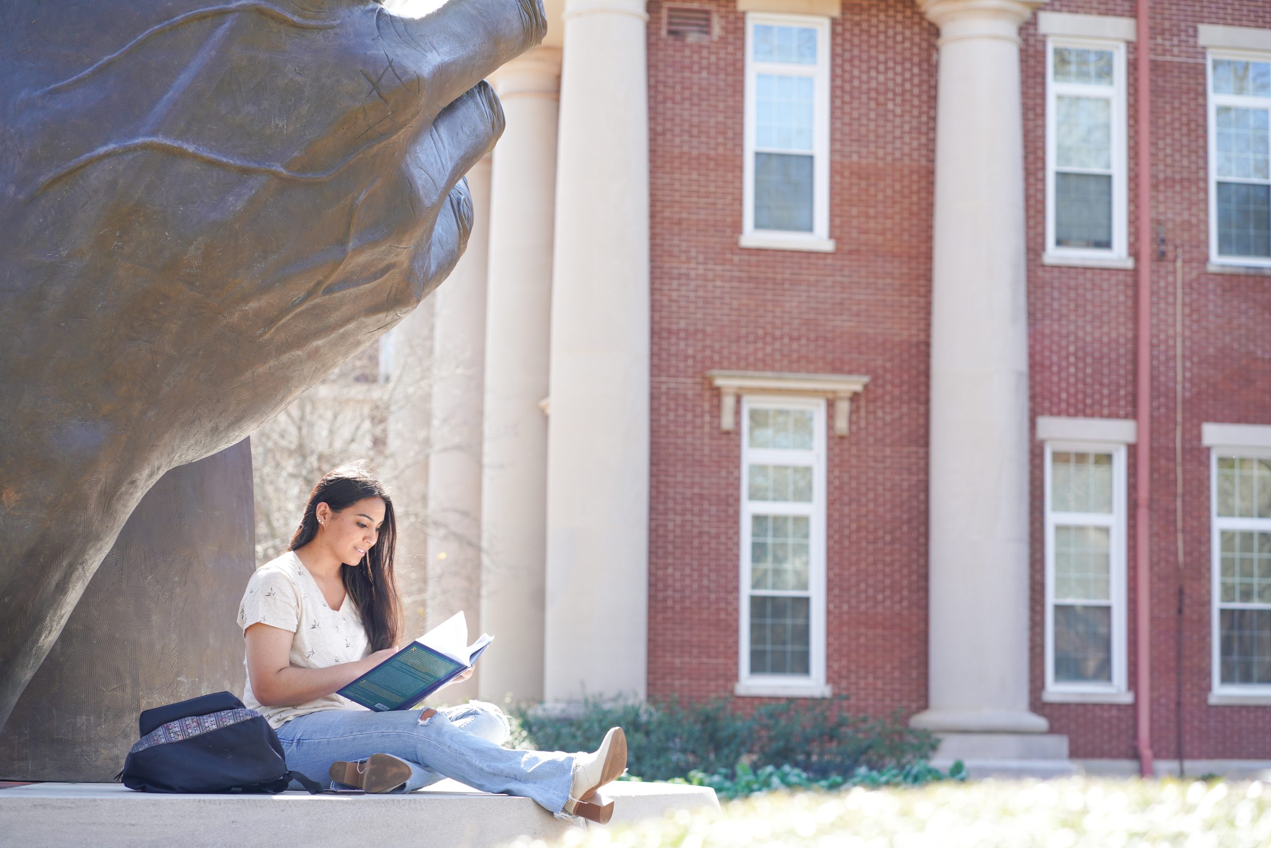一名学生在蒙特瓦洛大学校园的雕像下学习。vwin德赢官网